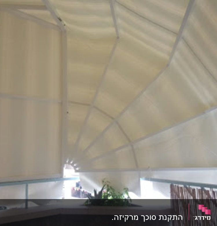 סוכך לבן מתוח מעל מרפסת עם צמחייה